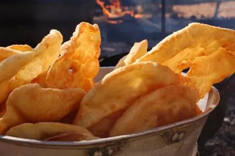 Tortas fritas doradas en canasta junto al fogón